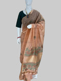 A peach-colored cotton saree with green and gold zari embroidery and border motifs, displayed on a white mannequin in a clothing store. The mannequin is also wearing a dark green blouse.